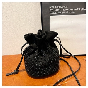 Close-up of black rhinestone bucket bag with drawstring closure and velvet texture