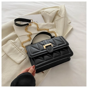 Detail of black quilted shoulder bag with gold metal buckle and leather chain strap