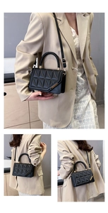 Detail of black quilted leather crossbody bag with braided handle and gold metal buckle