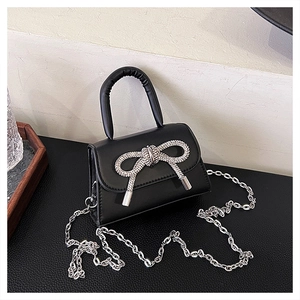 Détail du mini sac en cuir noir avec un nœud en strass argenté et une chaîne en métal