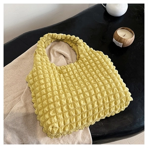 Detailed view of yellow bubble texture fabric on a stylish cloud pleated tote bag