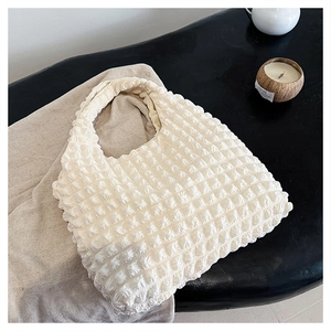 Detailed view of cloud bubble texture on a beige shoulder bag with popcorn pleat fabric