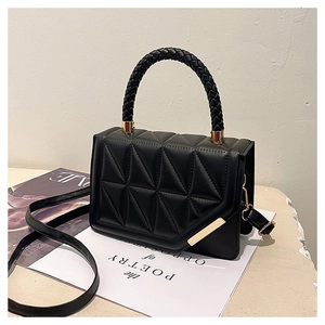 Detail of black quilted geometric texture bag with braided handle and gold hardware