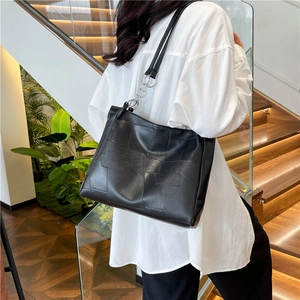 Black geometric patchwork tote bag with silver rings worn by a model in a modern setting