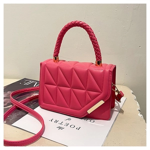 Detail of pink quilted crossbody bag featuring woven handle and gold hardware accents