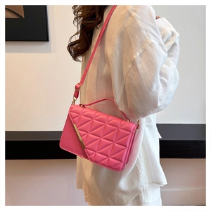 Detailed view of bright pink quilted crossbody bag with gold metal buckle and hand strap