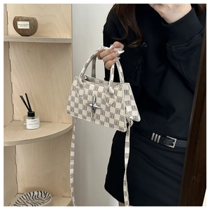 Detail of checkered plaid handbag with silver star buckle and crossbody strap