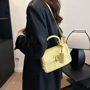 Fashionable lemon yellow leather crossbody handbag with round handle and lettered tag
