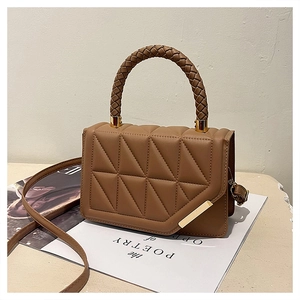 Detail view of tan crossbody bag with triangle quilting and woven round handle