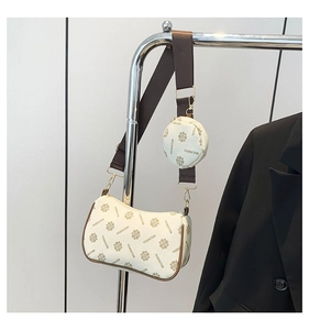 Detailed view of cream-colored floral crossbody bag with round coin purse and gold hardware