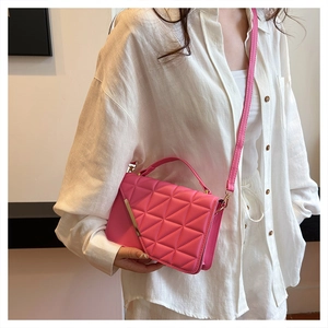 Detail of hot pink quilted shoulder bag featuring gold hardware and unique diagonal flap design