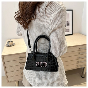 Detail of black crocodile texture handbag with pink letter print on interior setting