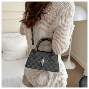 Detail of checkered crossbody bag with star metal buckle worn by a model in interior