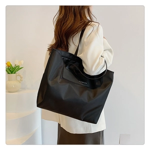 Fashionable black nylon tote bag shown from side view on model for everyday commute