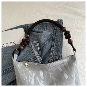 Detail of light gray pleated tote bag featuring bohemian wooden beads and rope handle