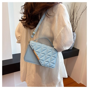 Detail view of light blue quilted shoulder bag with gold metal trim and detachable strap