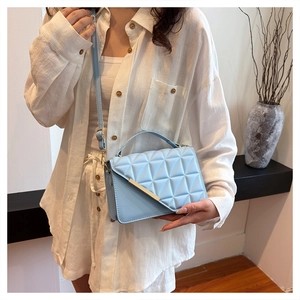 Detail of light blue quilted crossbody bag with gold metal trim and adjustable strap