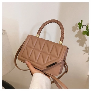 Detail of light brown square handbag showing triangle quilted texture and woven top handle