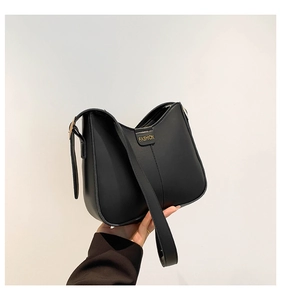 Detail of a minimalist black bucket bag with gold buckle and fashion text print