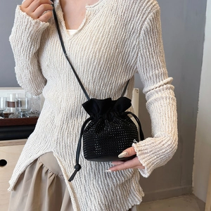 Sparkly rhinestone drawstring bucket bag with black strap worn by a model in casual outfit