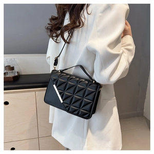 Detail of black geometric quilted shoulder bag with silver metal bar and top handle