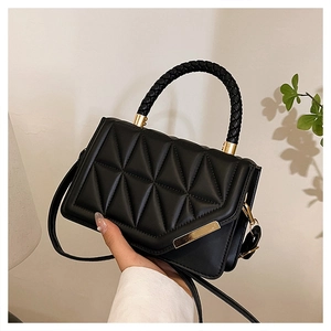 Macro shot of black quilted bag with woven handles and elegant gold metal hardware