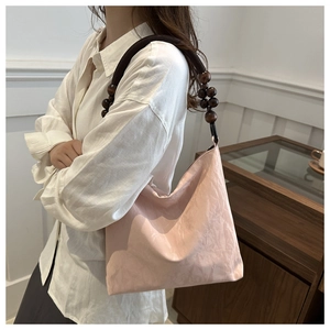Close-up of pink tote bag with unique dark brown wooden bead strap and leather texture