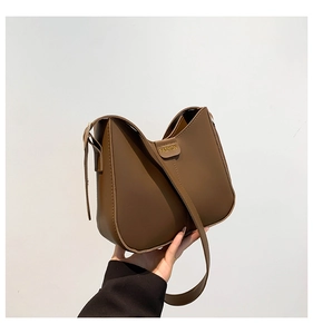 Detail of brown hobo bucket bag with fashion leather tag and smooth synthetic texture