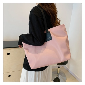 Detail of pink tote bag with black shoulder strap and FASHION label for daily commute