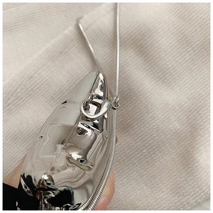 Detailed view of silver metallic face-shaped mini bag with glossy mirror finish and chain