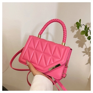 Detail of bright pink quilted crossbody bag with woven handle and gold hardware
