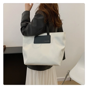 Detail of white nylon tote bag with black FASHION label and long shoulder handles