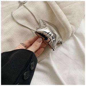 Close-up of a mini silver mirror-finish pillow bag with a sleek snake chain strap
