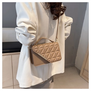 Detailed view of the diamond quilted texture and silver metal trim on the beige handbag