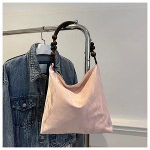 Close-up of pink tote bag with textured crinkle fabric and dark wooden bead handle
