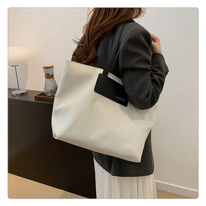 Detail view of large white nylon tote bag with black straps for office and travel use