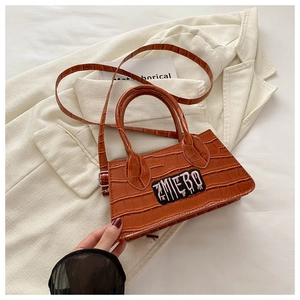 Detail view of orange-brown croc-embossed mini handbag with AMIEBO embroidery patch