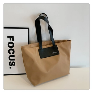 Close-up of khaki nylon tote bag with black Fashion tag and long shoulder straps