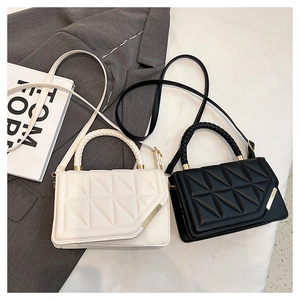 Close-up of quilted crossbody bags with woven ring handles in black and white finish