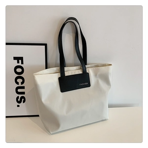 Close-up of cream white tote bag with black straps and fashion lettering detail