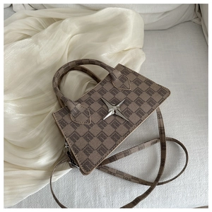 Detail of a brown checkered crossbody bag with silver star hardware on soft silk fabric