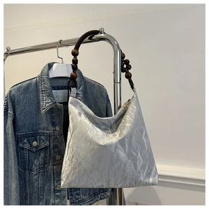 Detail of silver metallic tote bag with unique dark wooden bead shoulder strap detail