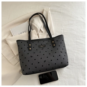 Detail of grey polka dot tote bag with black ribbon prints and gold rivet accents