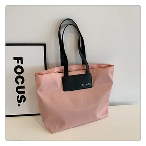 Detailed view of pink nylon tote bag with black fashion label and slim shoulder straps