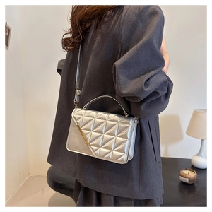 Close-up of quilted silver crossbody bag featuring golden metal trim on grey blazer