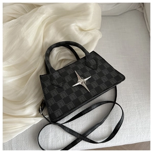 Detail of grey checkered crossbody bag with silver star ornament on textured fabric