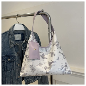 Détail d'un sac cabas blanc avec imprimés papillons violets et mini pochette assortie