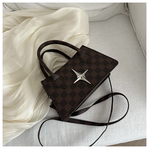 Detail of checkered pattern bag with silver star ornament on creamy fabric background