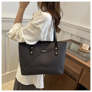 Detail of grey canvas tote bag with red polka dots and reinforced black straps