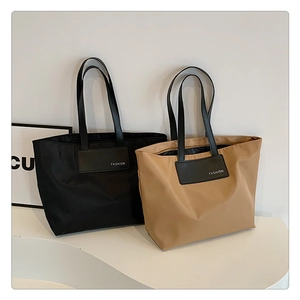 Close-up of minimalist nylon tote bags in black and khaki with leather fashion logo tag